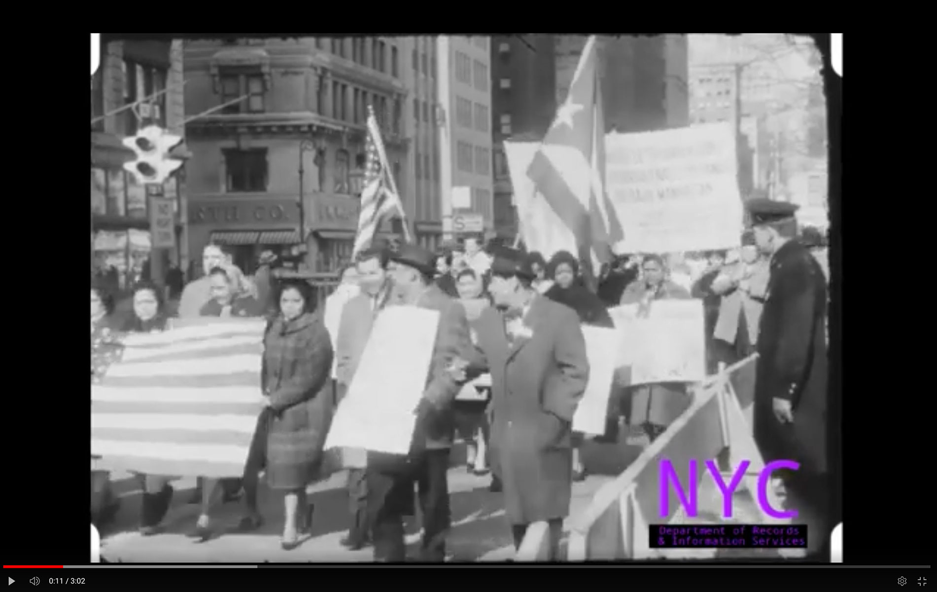 Protestors march, carrying signs and the Puerto Rican flag